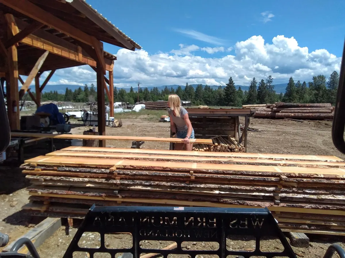 Mill worker beside fresh-cut lumber