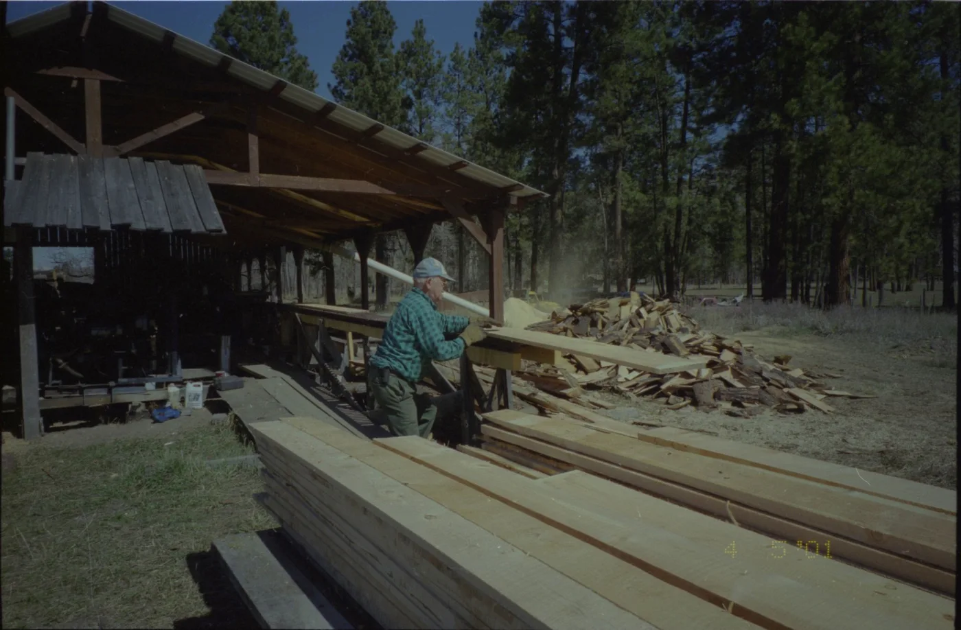 Mill worker handling fresh lumber coming off the sawmill in 2001